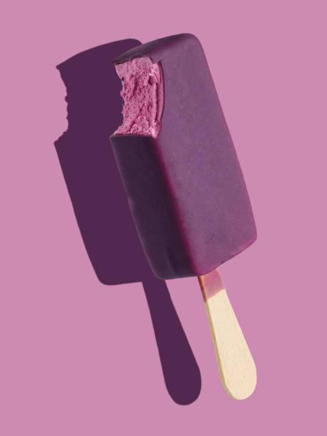 istock Bitten purple ice cream bar on a stick on purple background 1255954967