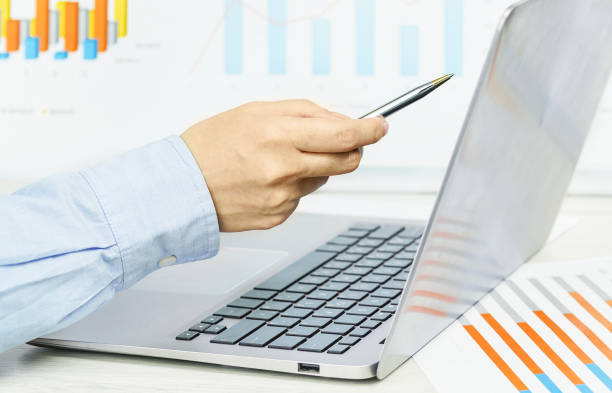 istock Finance. Female hand pointing at laptop screen financial graphs on desk 1255956257