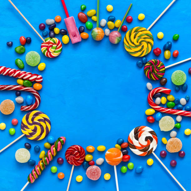 istock Colored candies, lollipops and marmalade on a blue background round frame. Top view, flat lay. 1255956314