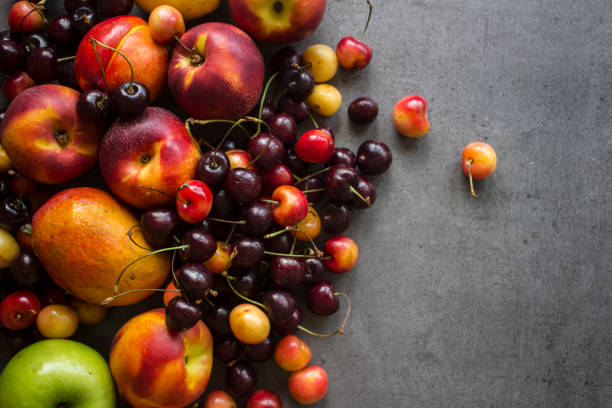 cherry, nectarines, mango and apples on textured background with copy space. - nectarine peach red market imagens e fotografias de stock