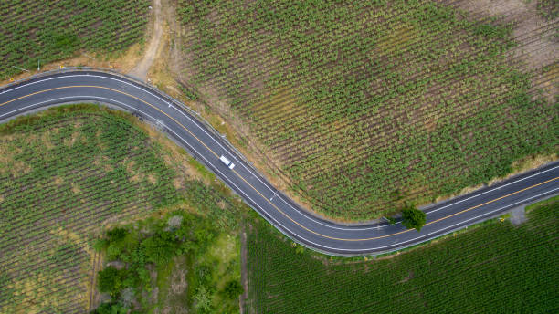 aerial view road curve construction. aerial above view of a rural landscape with a curvy road running through. aerial view of curving road through colorful spring agriculture fields. - 12026 imagens e fotografias de stock