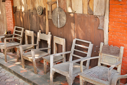 Tilt view along old thai chairs outside of a farm in Chiang Mai province