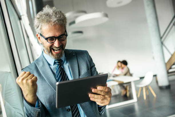 istock Happy senior businessman standing next to window 1255962484