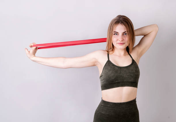 istock Young fit woman doing exercises with a resistance band isolated on gray 1255962655