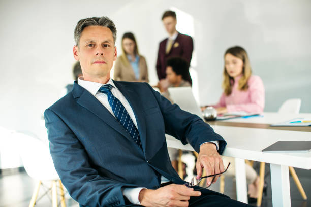 istock Senior businessman CEO sitting on the desk 1255962690