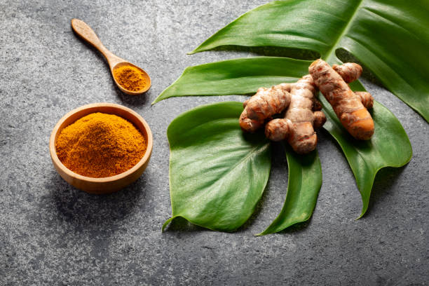 istock Turmeric powder and fresh turmeric root on grey concrete background. 1255965479