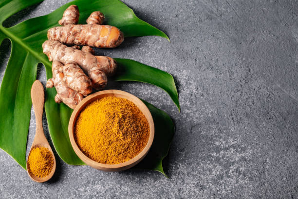 istock Turmeric powder and fresh turmeric root on grey concrete background. 1255965600