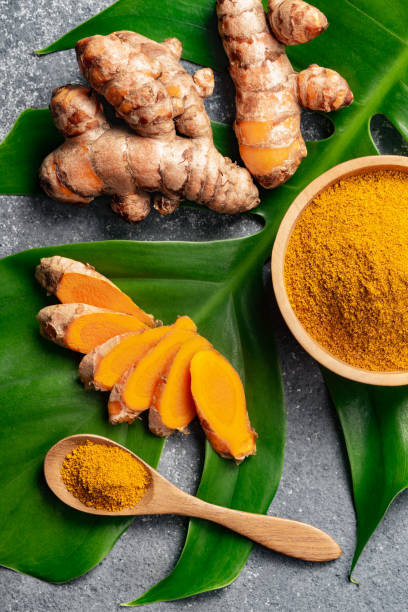 istock Turmeric powder and fresh turmeric root on grey concrete background. 1255965741