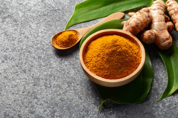 istock Turmeric powder and fresh turmeric root on grey concrete background. 1255965751