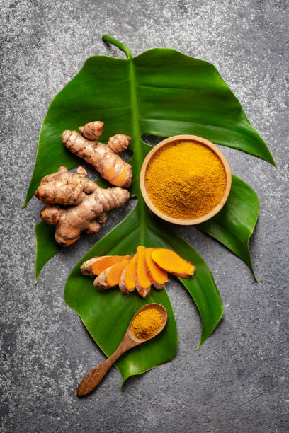 istock Turmeric powder and fresh turmeric root on grey concrete background. 1255965831