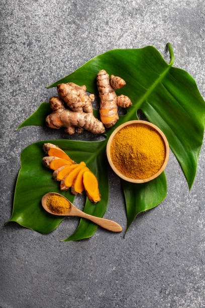 polvere di curcuma e radice di curcuma fresca su sfondo di cemento grigio. - curcuma foto e immagini stock