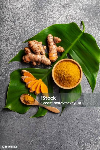 Turmeric Powder And Fresh Turmeric Root On Grey Concrete Background Stock Photo - Download Image Now