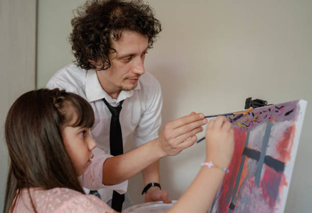 istock Father and kid drawing picture, using different acrylic paints and brushes.Lesson of art. 1255967379