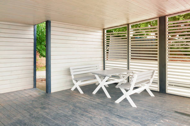 istock White table with benches in empty wooden gazebo or canopy sunny summer day. 1255967964