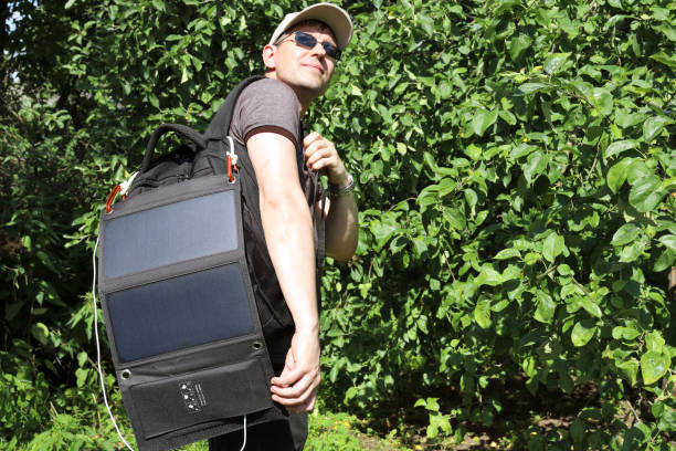 istock Young hiker with backpack behind him and solar charging panel on it stops and stops and looks back 1255968134