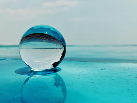 Lensball placed on the edge of a swimming pool reflecting in the water.