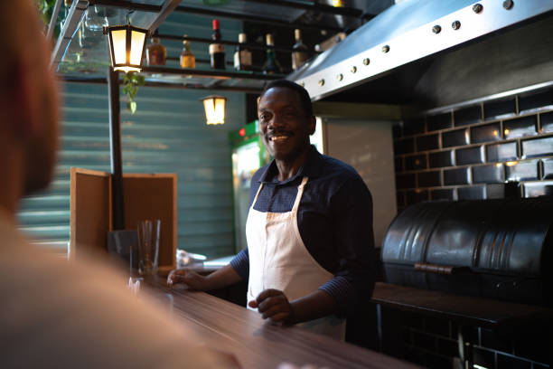Barista serving ant talking to customers at the restaurant