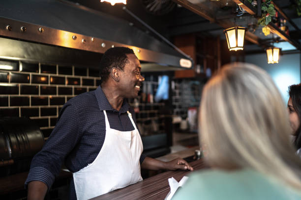 istock Barista serving ant talking to customers at the restaurant 1255972502