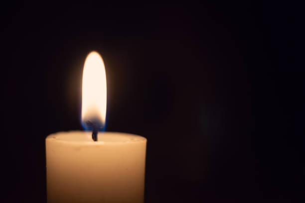 istock White candle with a flame on a black background close up with copy space 1255974741