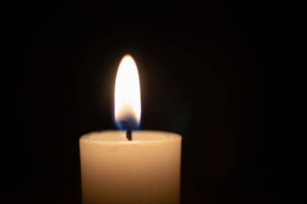 istock White candle with a flame on a black background close up with copy space 1255975187