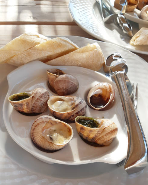 istock A plate with cooked snails on wooden table. 1255976188