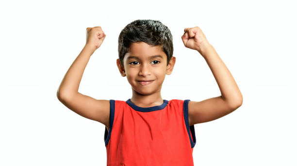 istock Little school boy standing and raising hands up and smiling 1255980566