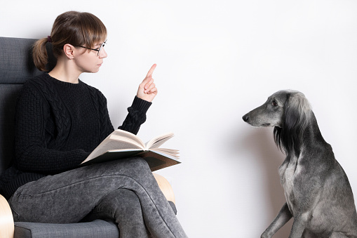 Beautiful woman scolds and reports her dog. greyhound sduty read.