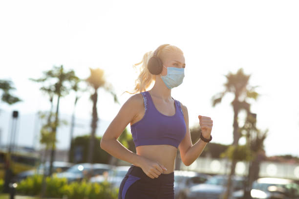istock Young woman running and wearing a protective face mask. 1255986325