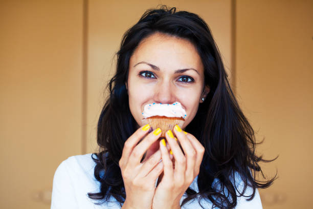istock Young woman eating a cupcake 1255986328