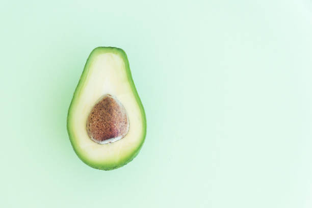 istock half of avocado with pit on light green  background 1255987773