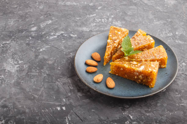 istock Traditional turkish candy cezerye made from caramelised melon, roasted walnuts, hazelnuts, pistachios in blue ceramic plate on a black concrete background. side view, flat lay, copy space. 1255989046