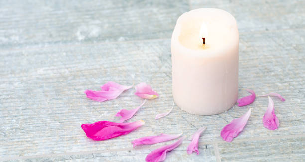 istock Beautiful pink peony petals and white candle on grey stone background with copy space for your text top view. 1255989558