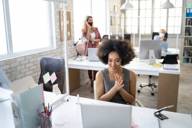 istock Afro business woman disinfecting her hands while working in office 1255990881