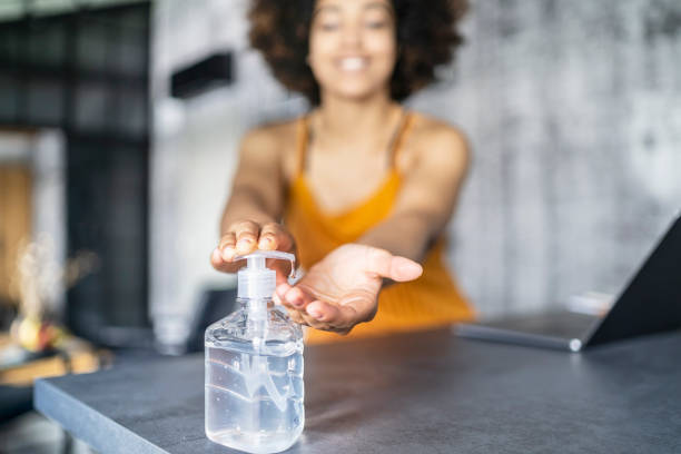 istock Afro American woman disinfecting her hands while working in office 1255990938
