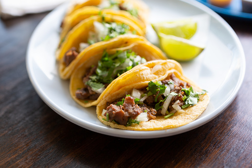 A view of a platter of street tacos, in a restaurant or kitchen setting.