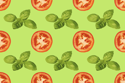 Seamless pattern of tomato slices and basil leaves on a green background. A simple drawing for the surface of packaging, textiles.