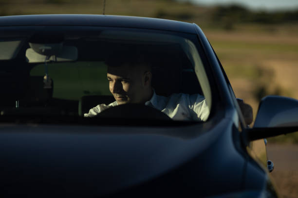 istock Young man sitting in car on country road 1255996620