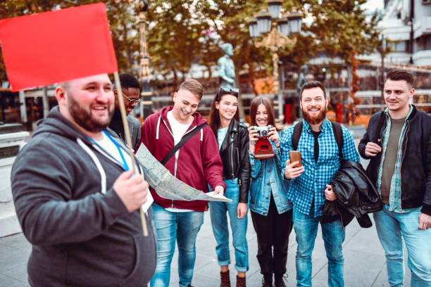 istock Tour Guide With Flag Leading Tourists Through Foreign City 1255997612