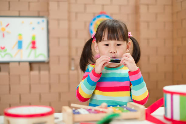 istock toddler girl play harmonica at home for home schooling 1255998565
