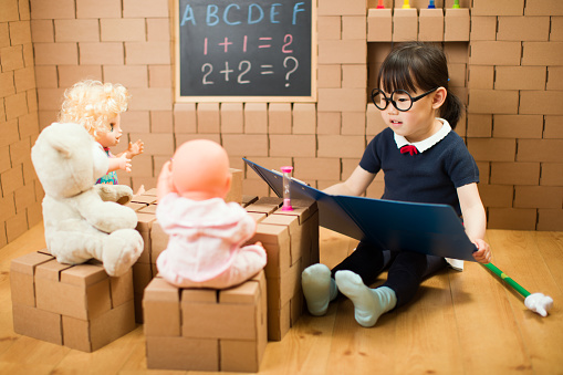 toddler girl pretend play as a teacher at home