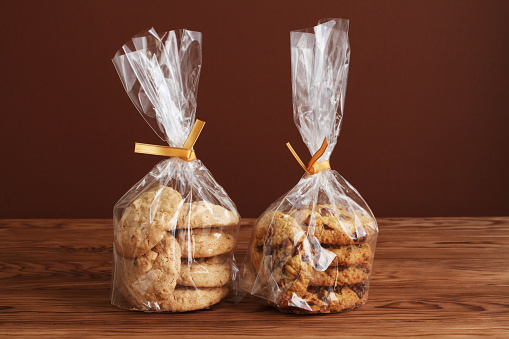 Oatmeal cookies with walnuts and raisins and almond cookies in a transparent bags on a wooden table. Closeup