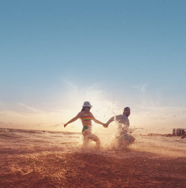 Young hispanic couple running into the water