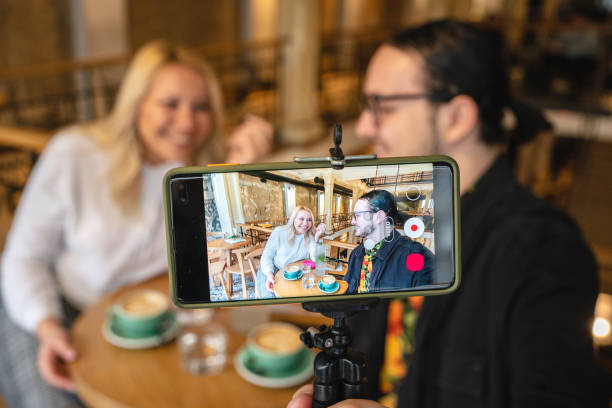 istock Couple filming a vlog through a mobile phone screen at a cafe 1256004428