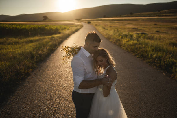 istock Bride and groom standing on countryside road  in a sunset light 1256005168