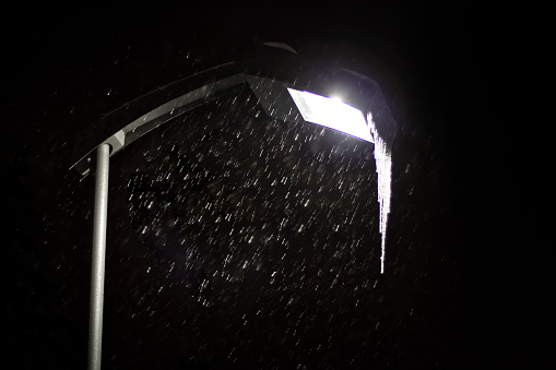 wet snow falling  in the night illumination against dark sky
