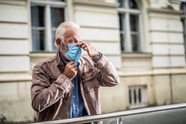 istock Senior man putting on a protective face mask. 1256014099