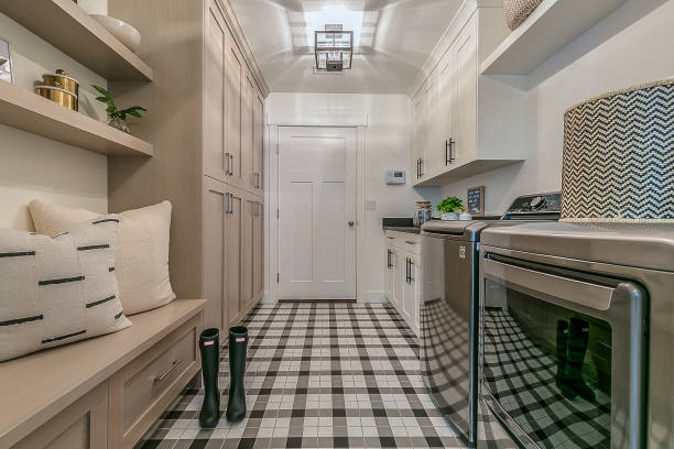 Immaculate mudroom and laundry room combo Rain boots and gingham decorated flooring in new custom home utility room stock pictures, royalty-free photos & images