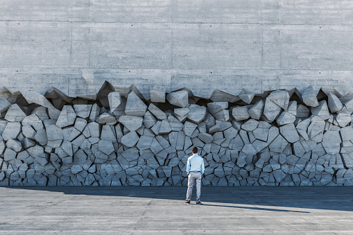 Businessman standing in front of breaking wall. This is entirely 3D generated image.