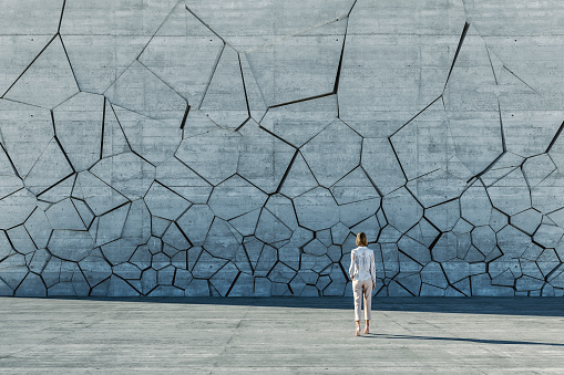 Businesswoman standing in front of breaking wall. This is entirely 3D generated image.