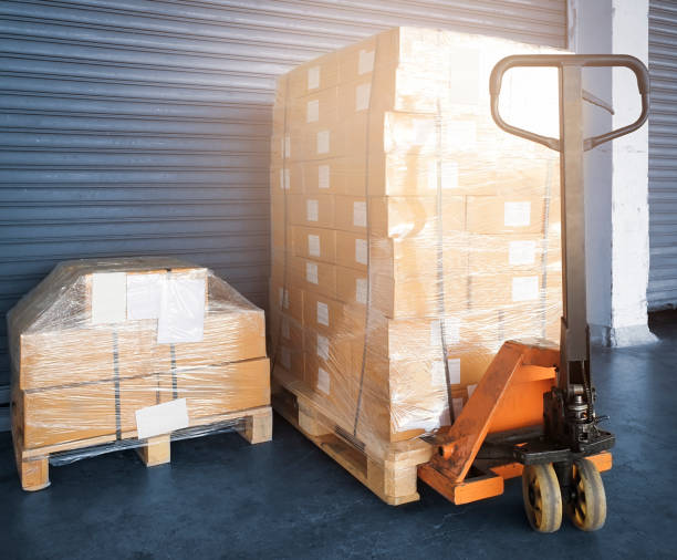 istock Hand pallet truck with stack of package boxes wrapping plastic on wooden pallets. Shipment cargo export. Warehouse industry delivery, Logistics and transport. 1256024730